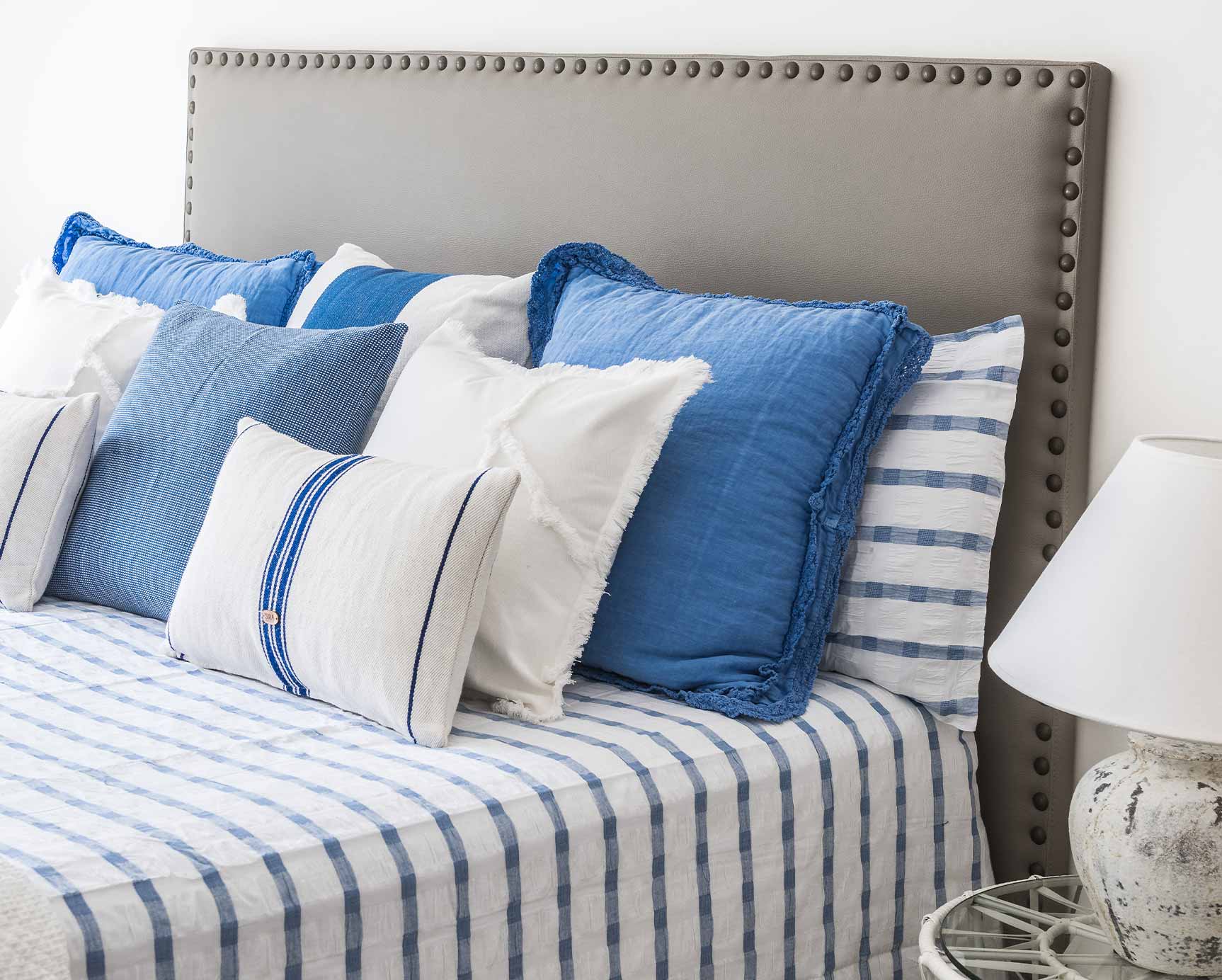 Cama decorada con cojines blancos y azules Cama decorada con cojines blancos y azules