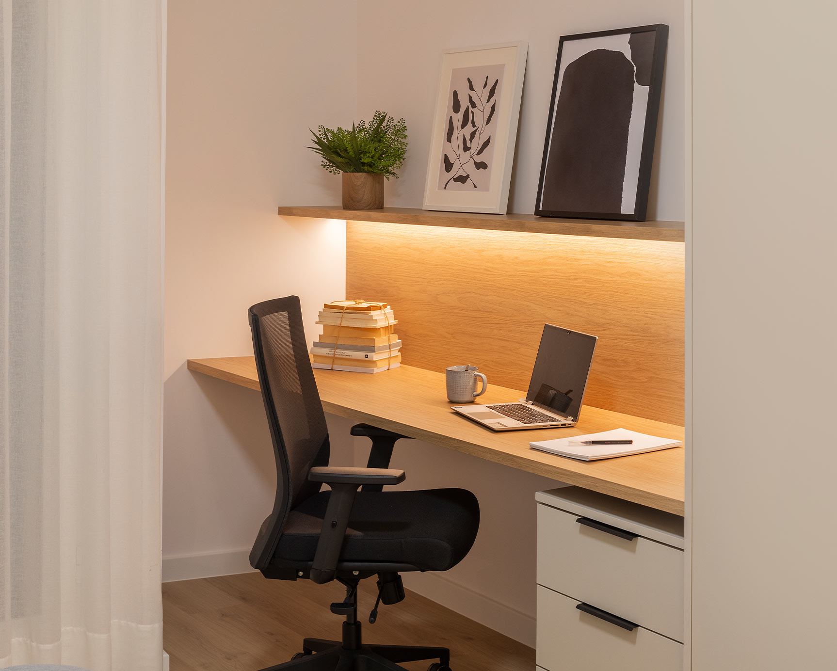 Escritorio en dormitorio decorado con cuadros y plantas