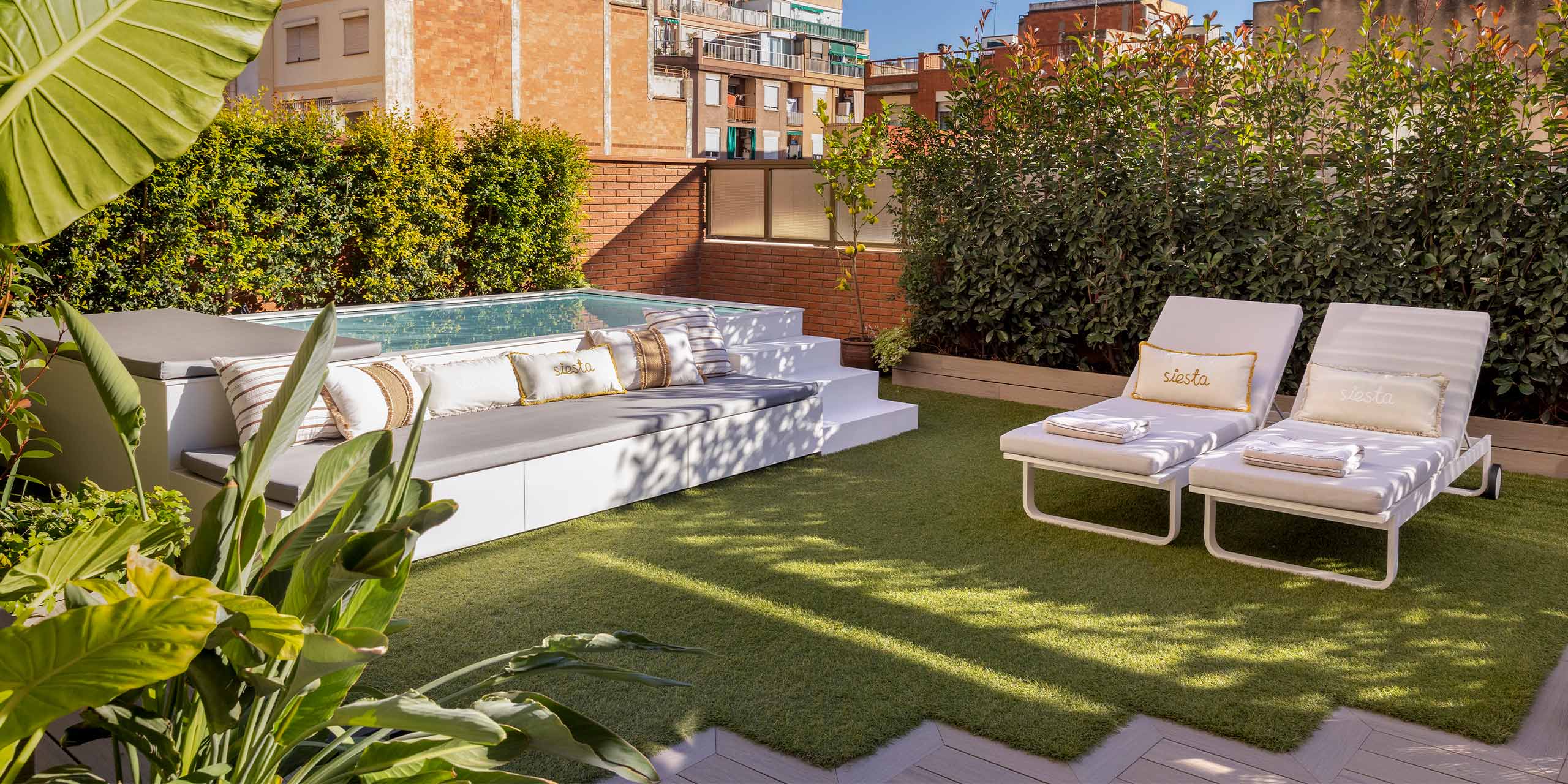 Sofá exterior con piscina y césped